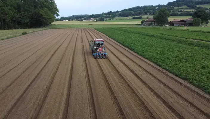 Vue aérienne d’un tracteur au travail sur une parcelle labourée