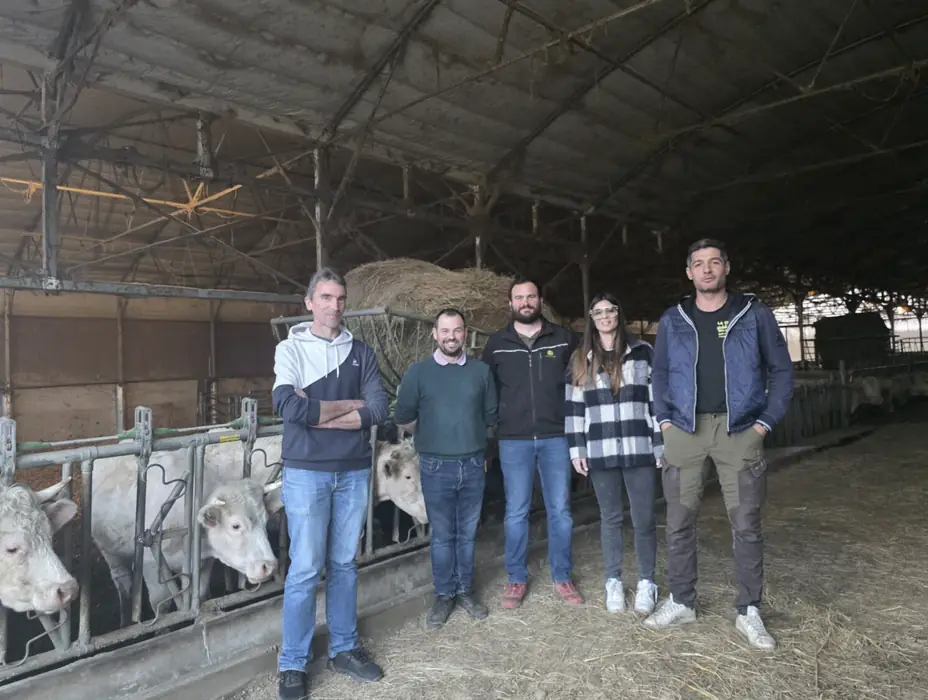 Cinq membres d’AGRIS A7 posent ensemble dans une stabulation, devant leurs vaches