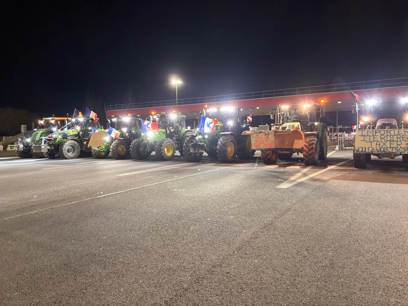 Convoi de tracteurs aux phares allumés sur la chaussée du péage de Reventin-Vaugris, de nuit